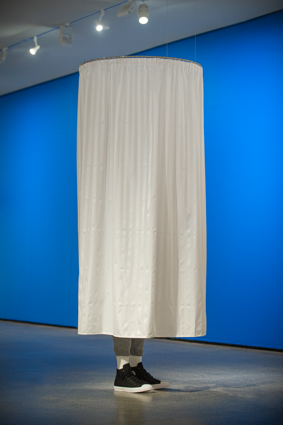 Artwork by Wayne Youle with sneakers peeking out from white shower curtain