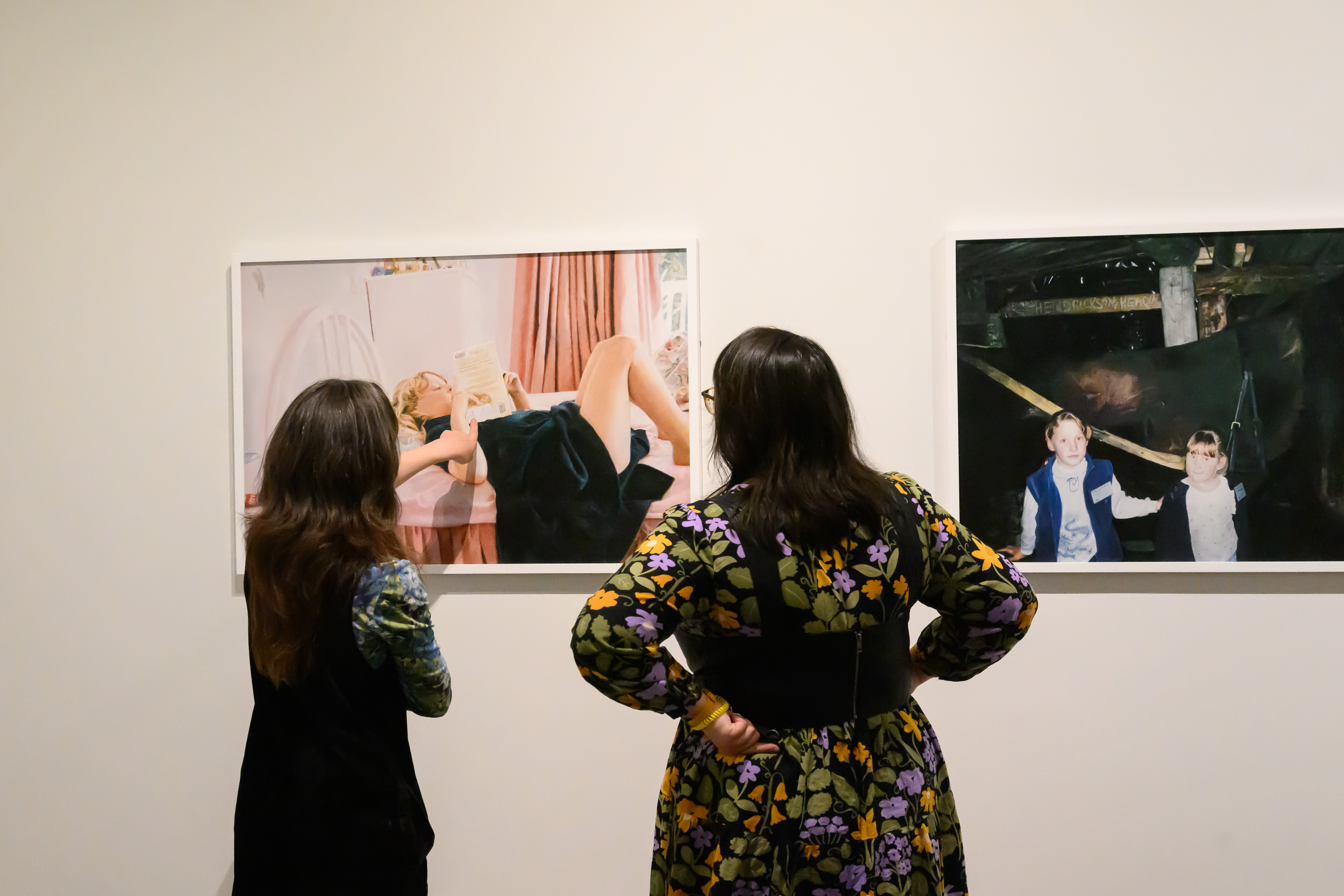 Two women examining drawings by Grace Crothall in The Brood