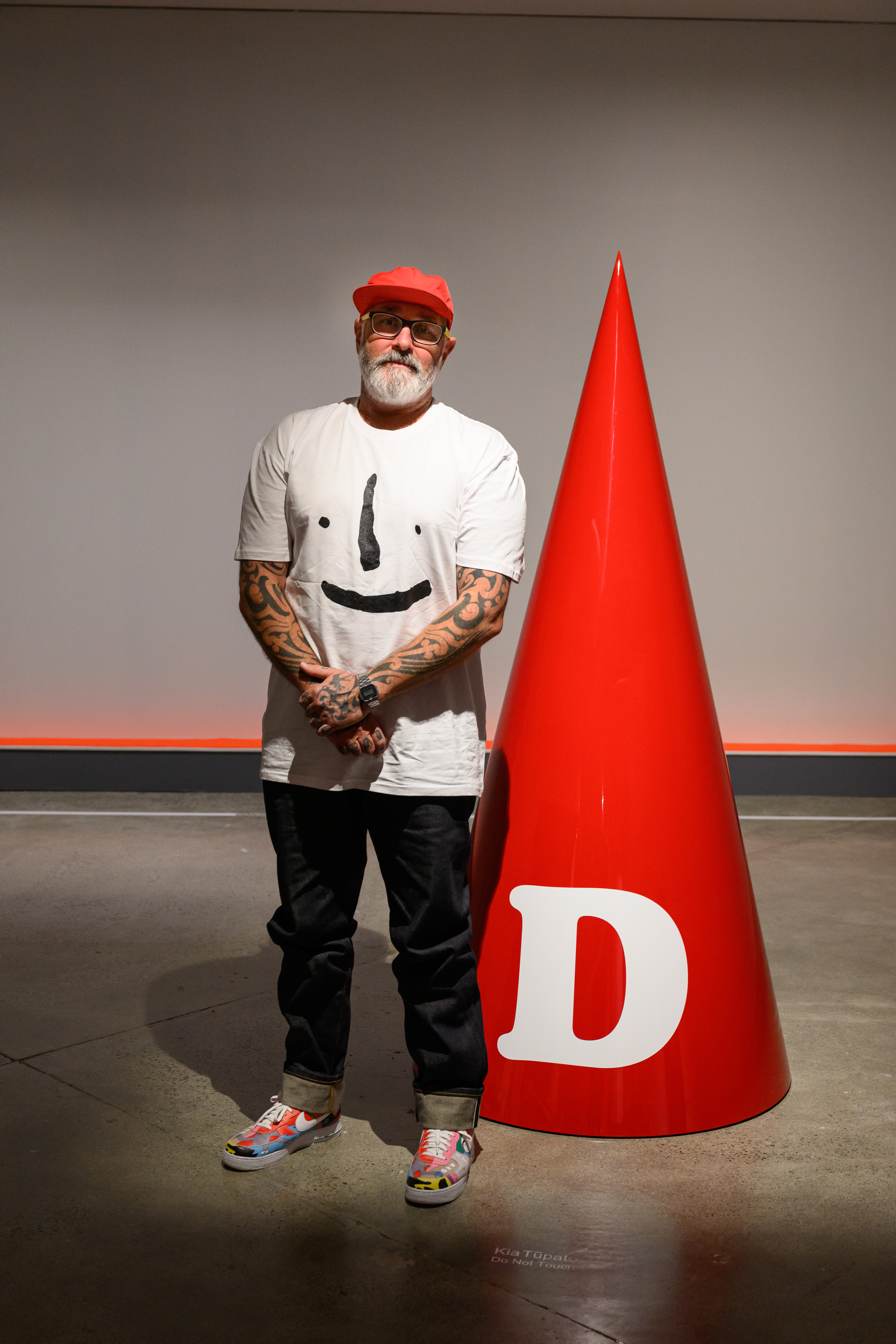 Artist Wayne Youle stands next to giant orange dunce cap